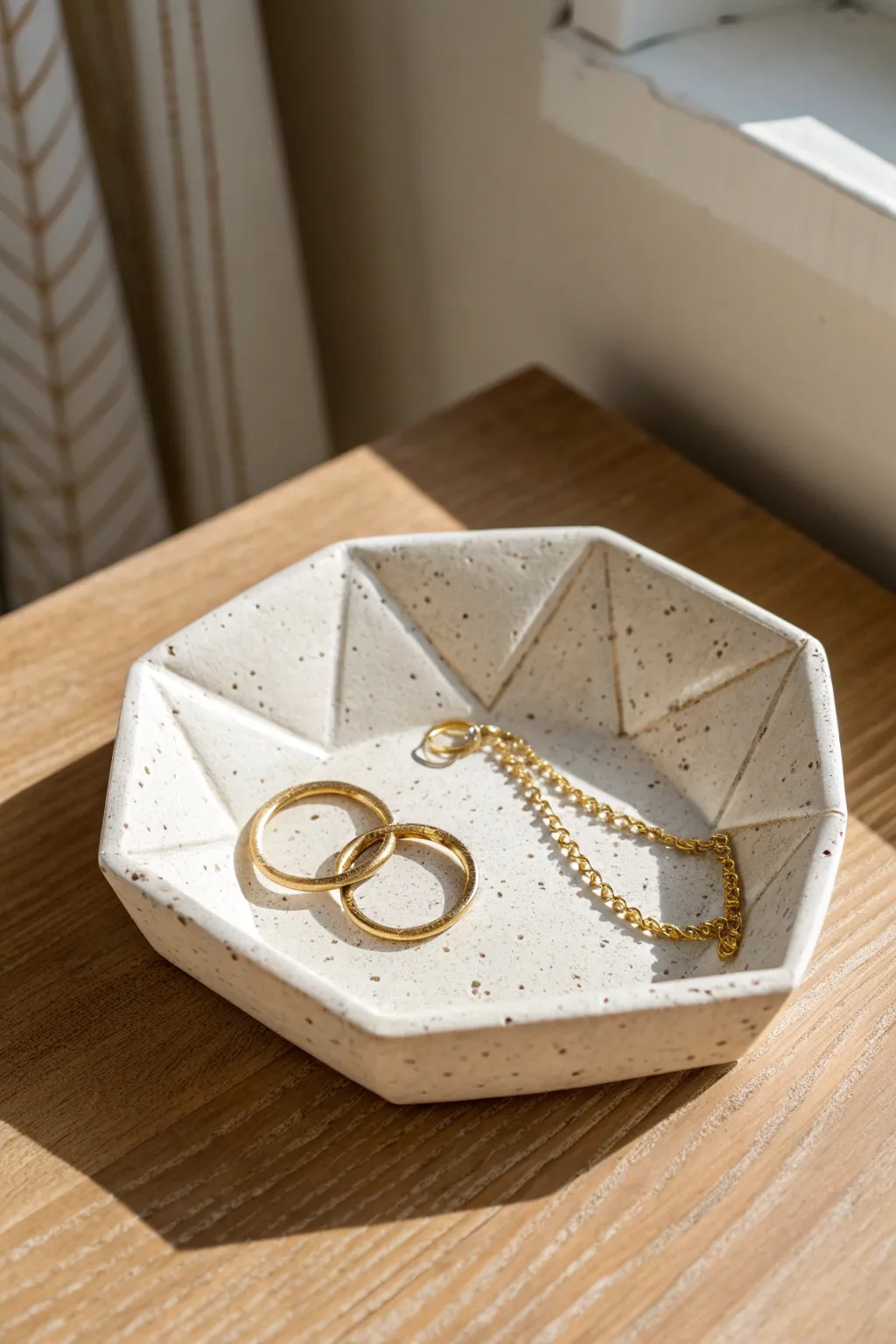 Faceted geometric pottery tray styled with minimalist jewelry for a modern, serene look