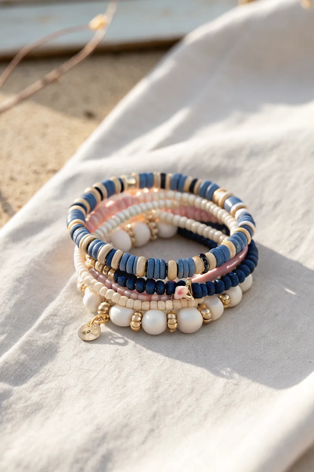 Mismatch preppy clay bead bracelet stack with stripes, gradients, pearls, and gold spacers in sunlit contrast