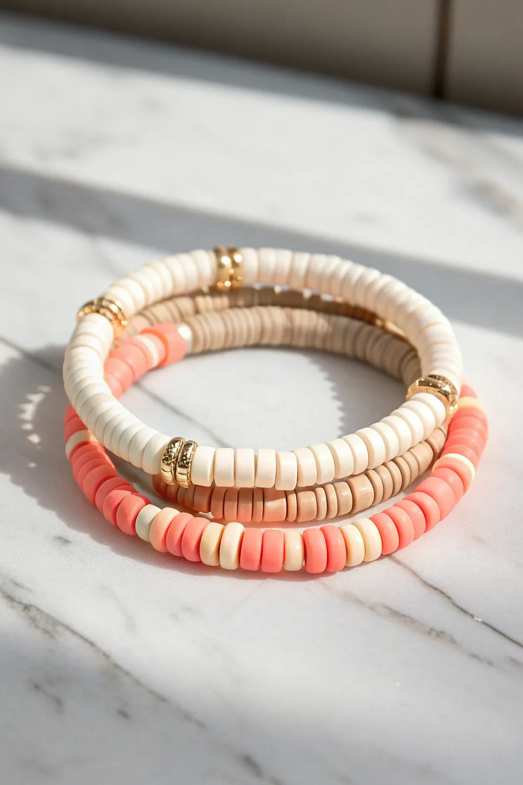 Cream, tan, and blush clay heishi stack finished with one neon pop spacer for preppy charm.