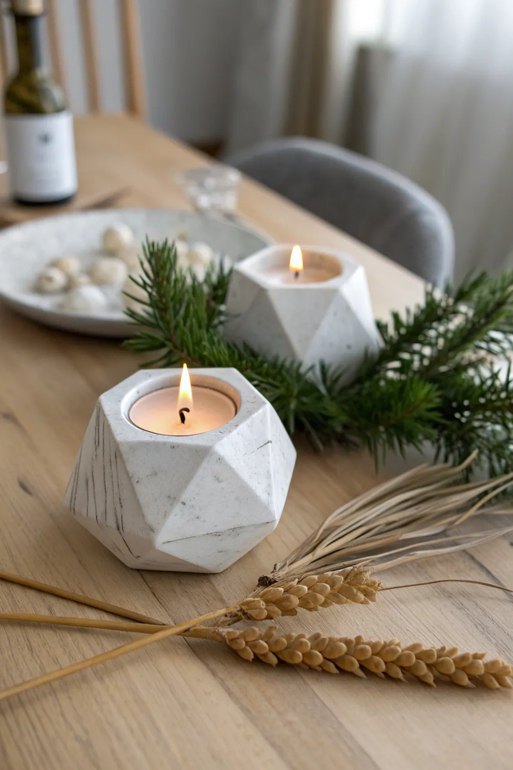 Faceted clay tea light holder casts a cozy Christmas glow with pine on a minimalist table.
