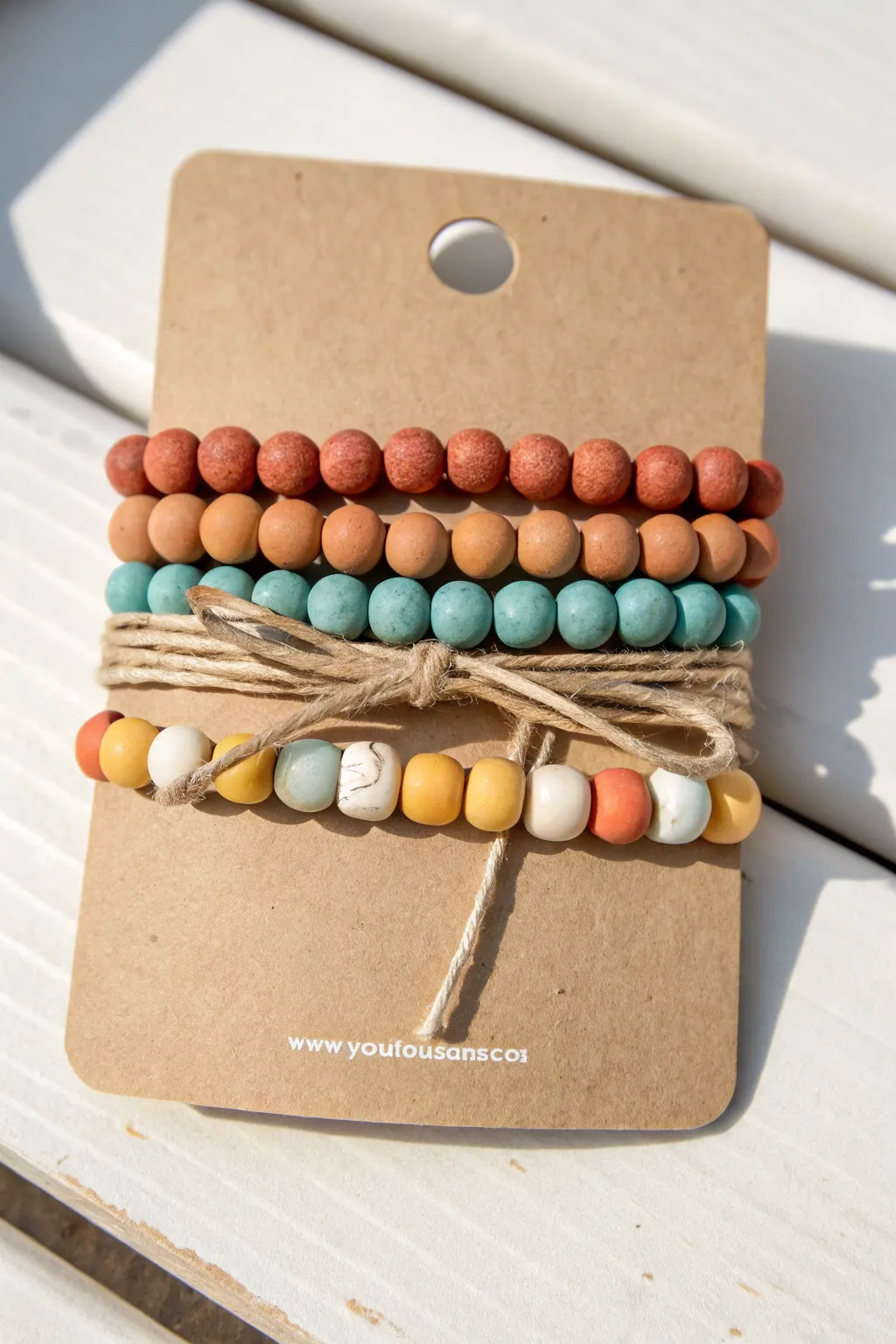 Shop-ready clay bead bracelet set on kraft card packaging, minimalist boho vibe with bold color pop.