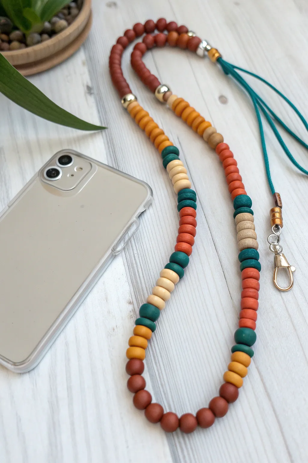 Convertible clay bead lanyard doubles into a wristlet, with a clear phone case attachment detail.