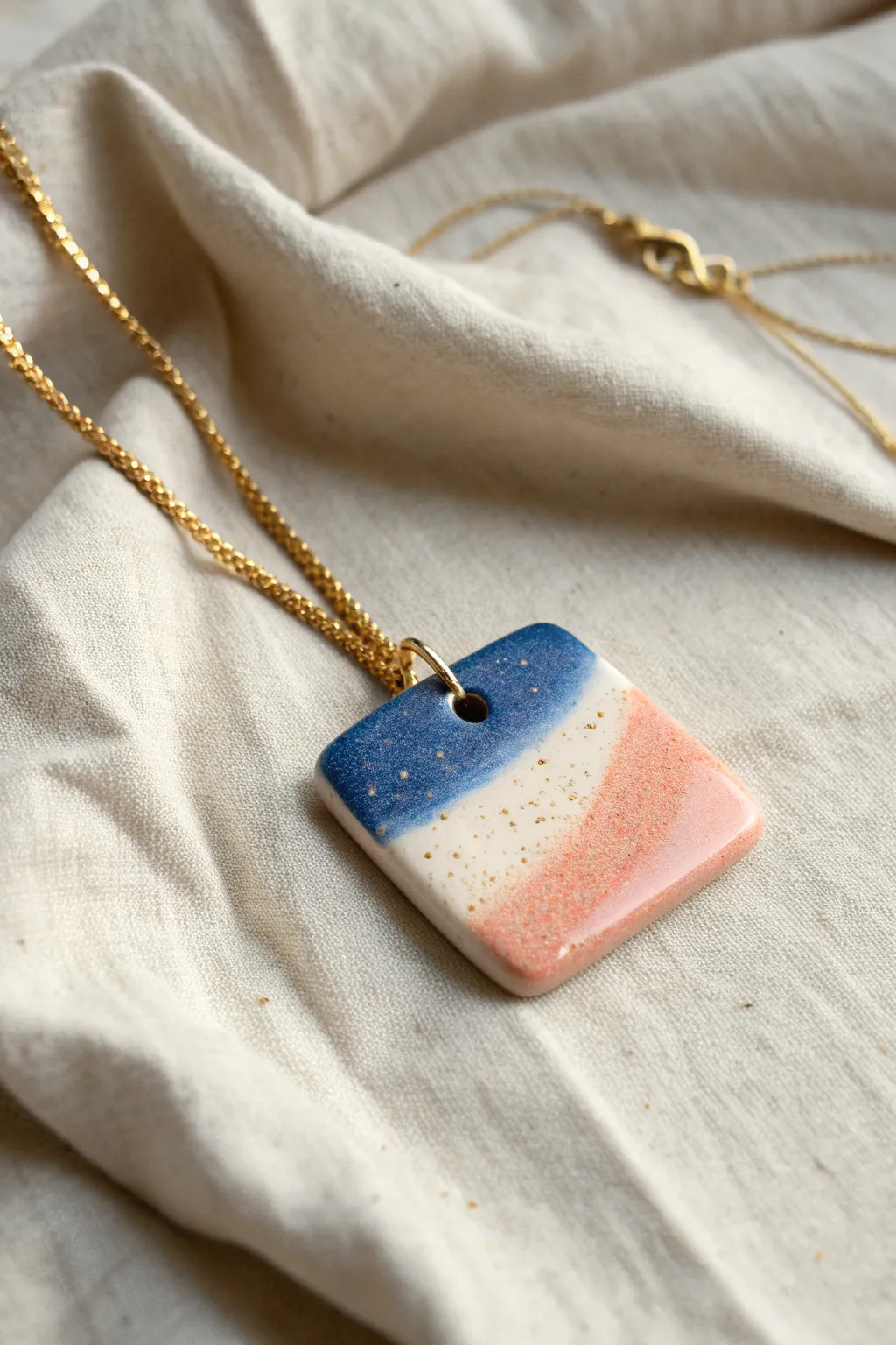 Tiny glazed tile pendant in bold cobalt and blush, styled on linen for minimalist boho vibes.