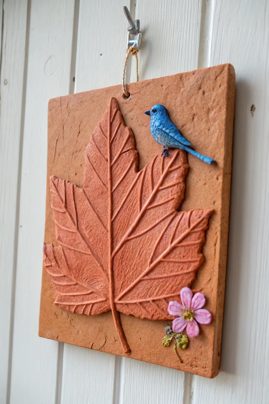 Minimal clay wall plaque with leaf texture and tiny bird, bright modern boho decor.