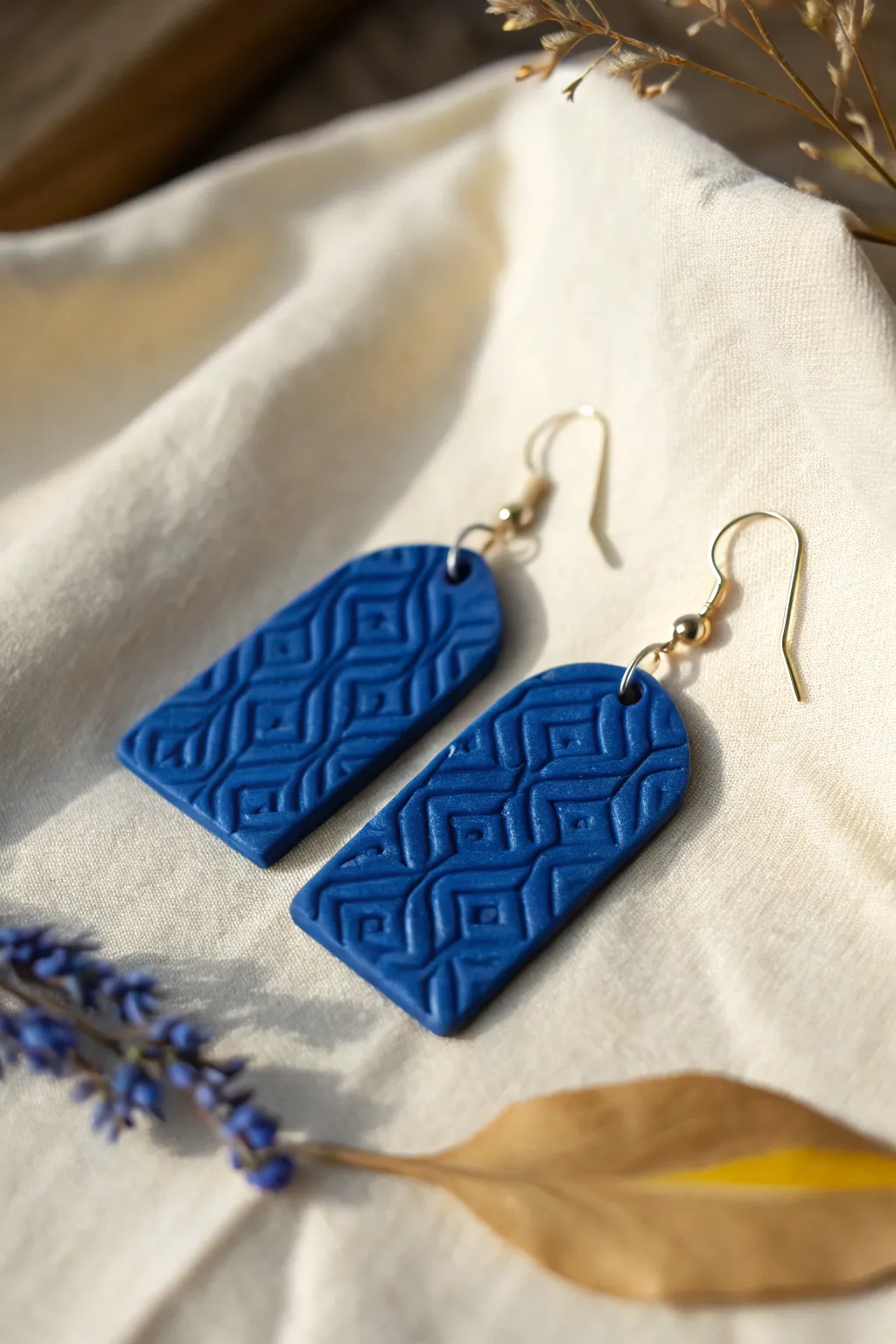 Cobalt polymer clay earring with baked extruded-stamp texture, clean Scandi boho contrast.