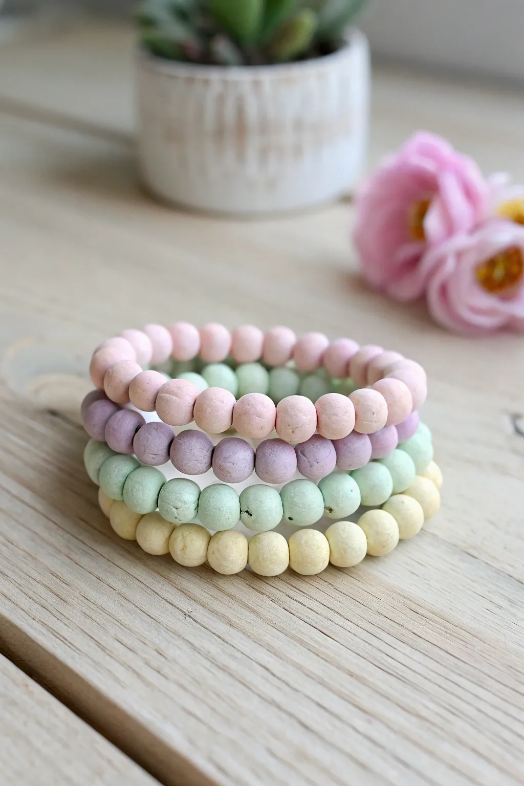 Soft pastel clay bracelet stack in blush, lavender, mint, and butter yellow on light wood.