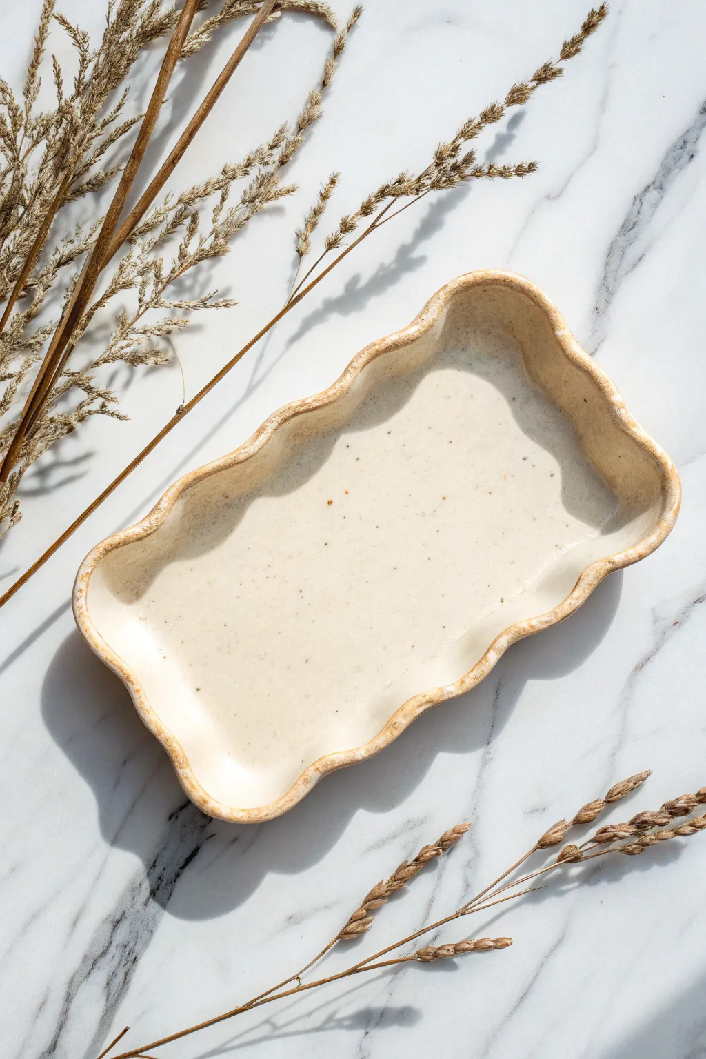 Creamy wavy rim catchall tray on marble, a calm minimalist clay dish idea with soft shadows