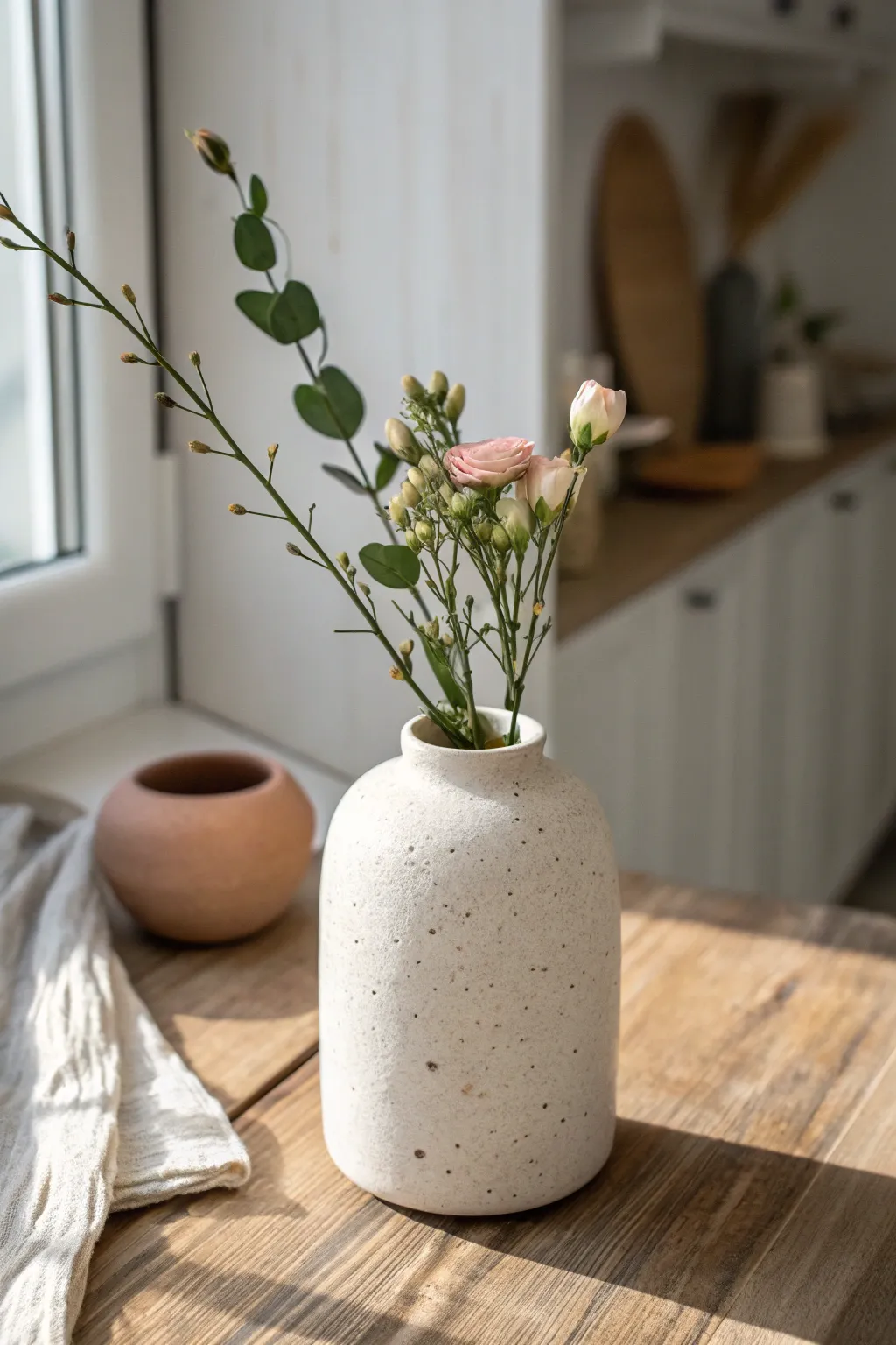 Minimal air dry clay cylinder bud vase with delicate stems, perfect for a clean Scandinavian counter.