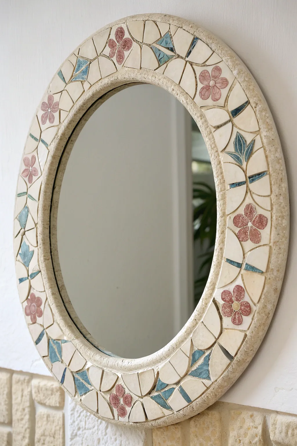 A chic round mirror framed with floral ceramic shards and smooth grout for modern boho charm.