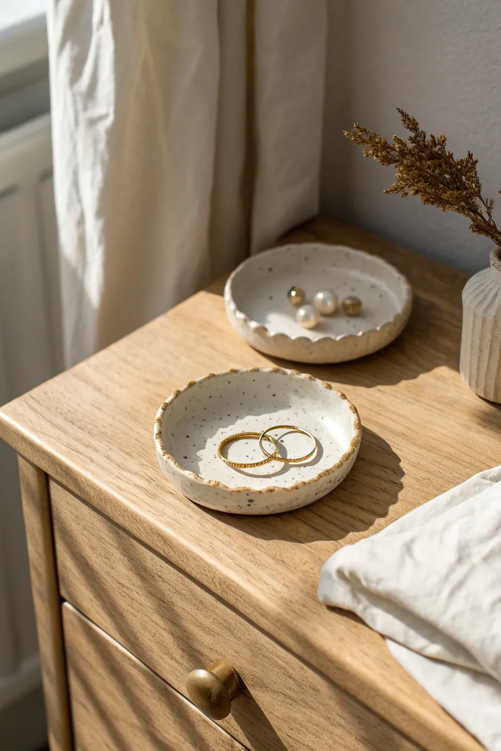 Minimal clay ring dishes in soft neutrals, styled with jewelry for a calm bedside moment.
