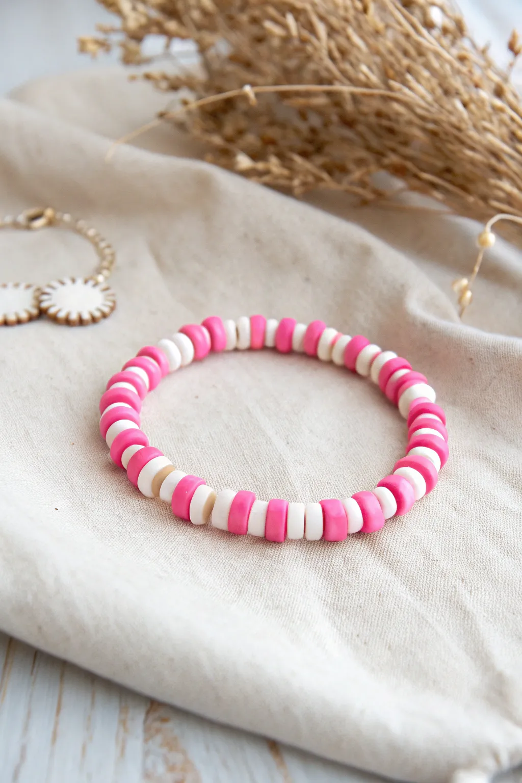 Bubblegum pink and white clay disc bead bracelet with clean candy stripes on soft linen.