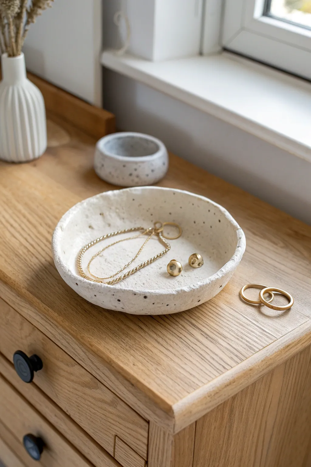 Simple pinch-pot tray keeps earrings and a fine chain tidy with handmade, softly imperfect charm.