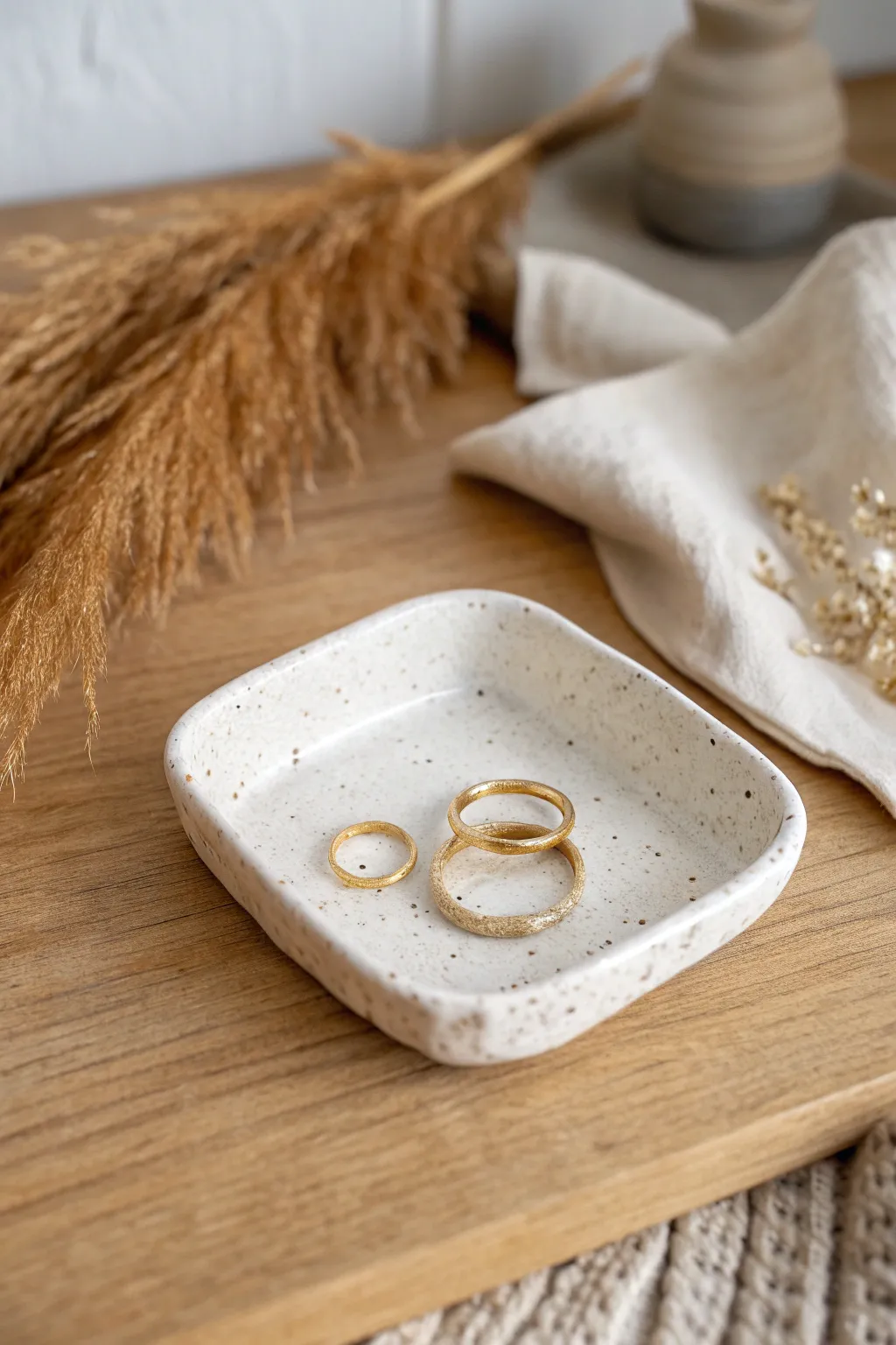 Petite pinched-corner slab dish, matte finish, cradling rings in a calm studio scene.