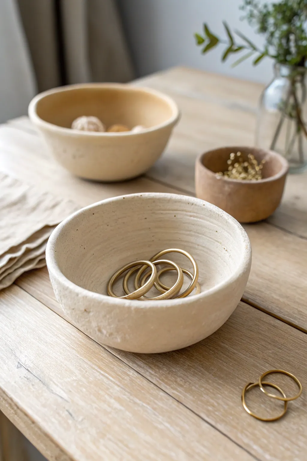 Coil built mini bowl with gentle coil texture, holding rings and hair ties on light wood.