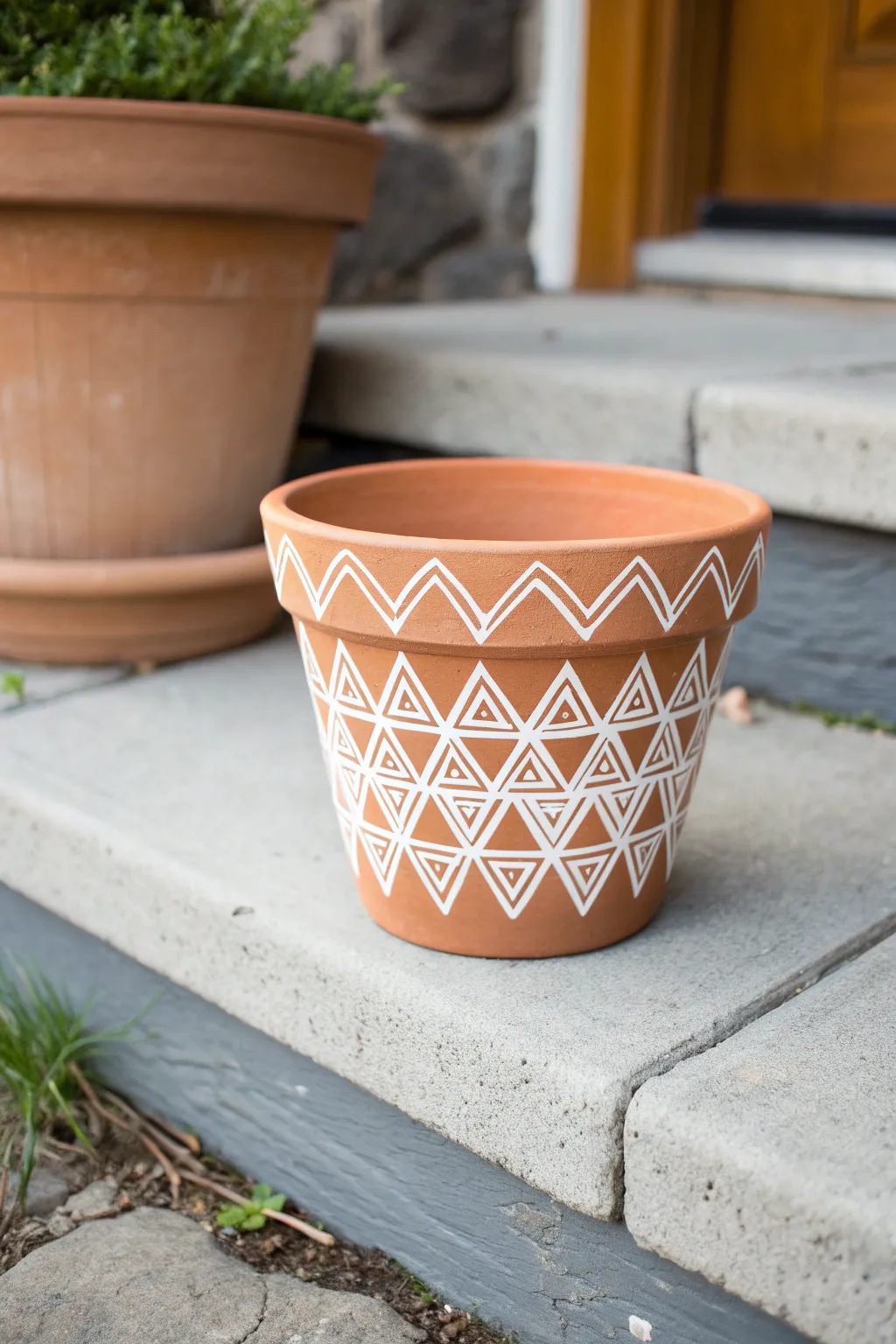 Crisp geometric stencil on a minimalist clay pot, perfect for a clean porch style.