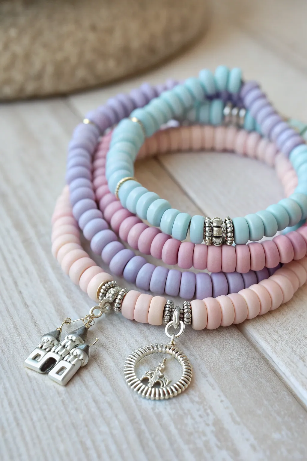 Pastel clay disc bead bracelet stack with silver spacers and a tiny castle charm