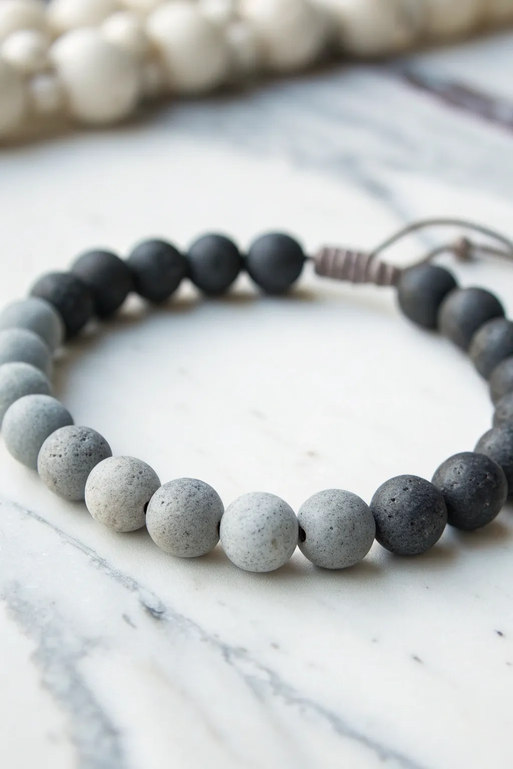 Light-to-charcoal ombré grey clay bead bracelet, minimal and modern on bright marble.