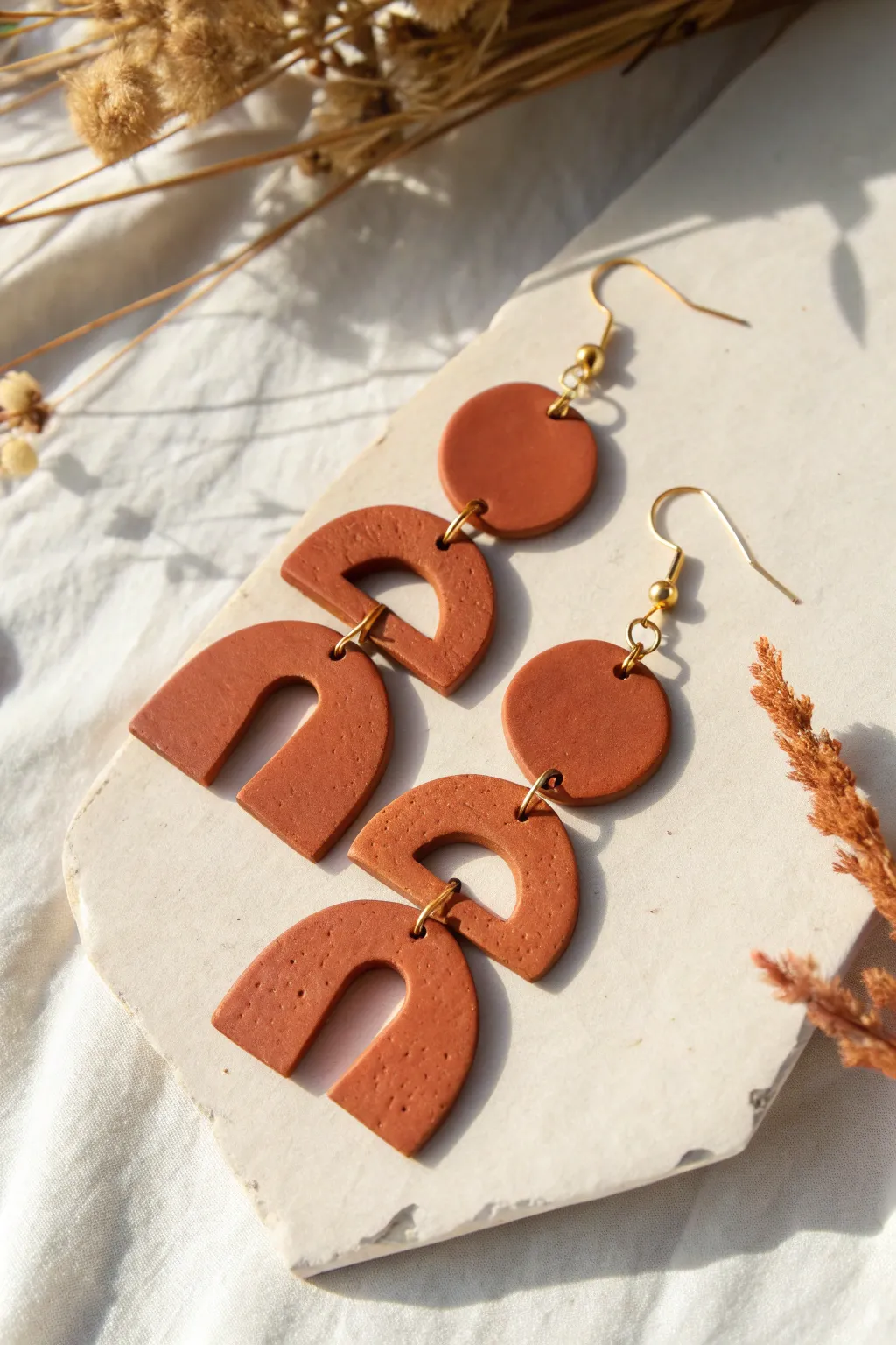 Matte clay dangle earrings with crisp cutouts, Scandinavian minimal with a soft boho touch.
