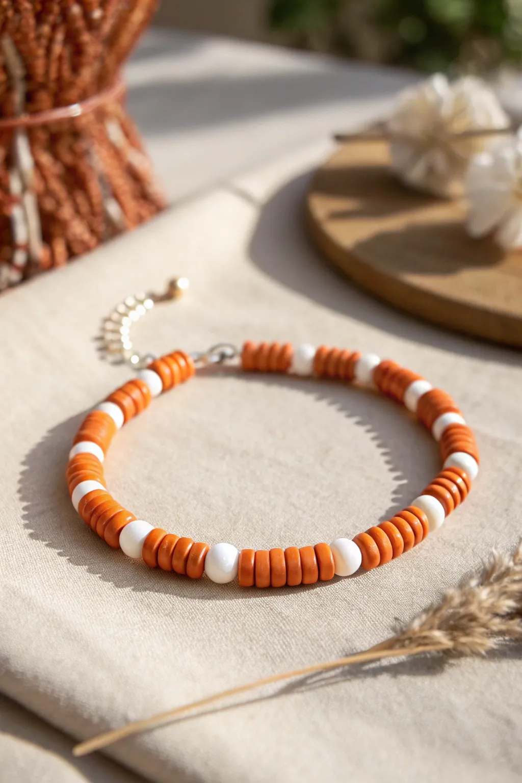 Orange and white striped clay disc bead bracelet on linen, minimal and crisp with soft shadows