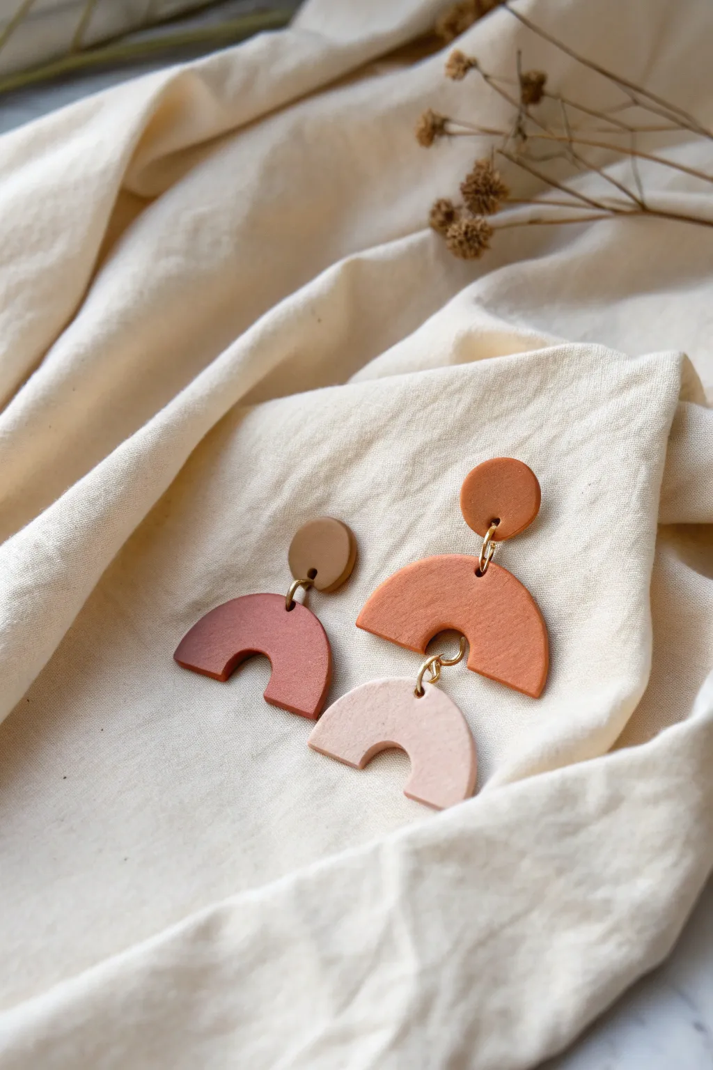 Bold geometric oven-dry clay earrings in earthy tones, matte finish, styled simply on linen.