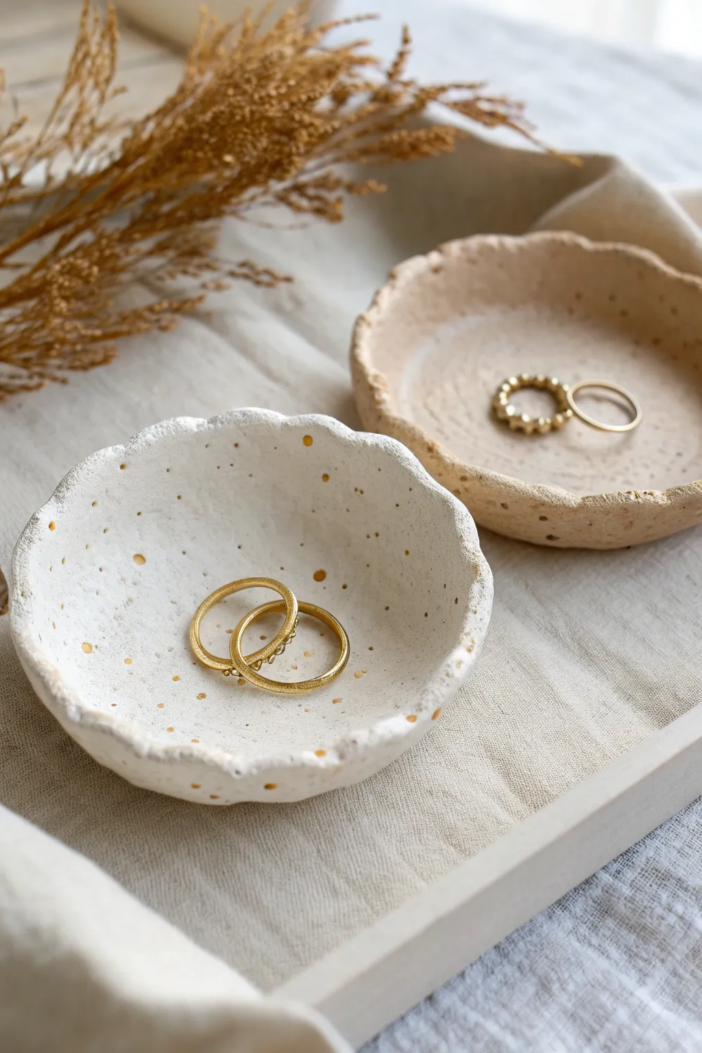 Textured paper clay ring dishes with soft ridges and dots, styled simply with gold rings