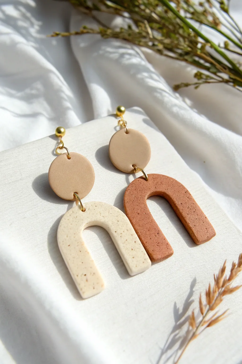 Circle-and-arch polymer clay statement drops in warm neutrals, clean white styling, soft shadows