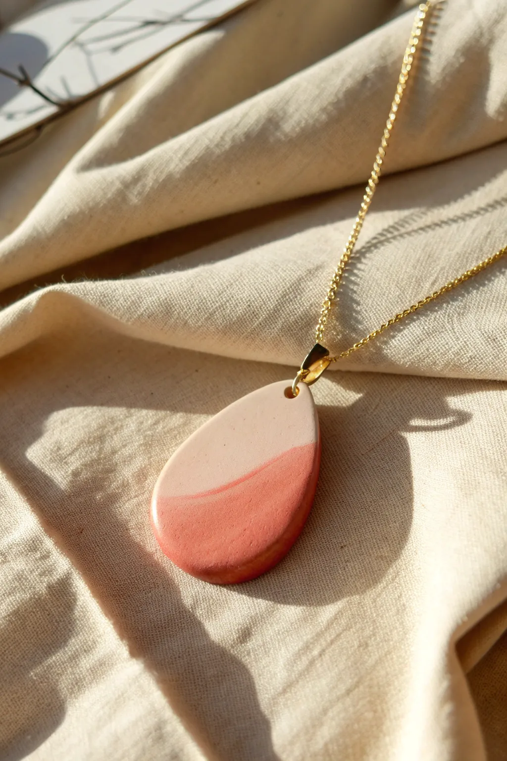 Classic teardrop polymer clay pendant with a soft blush-to-terracotta gradient on linen.