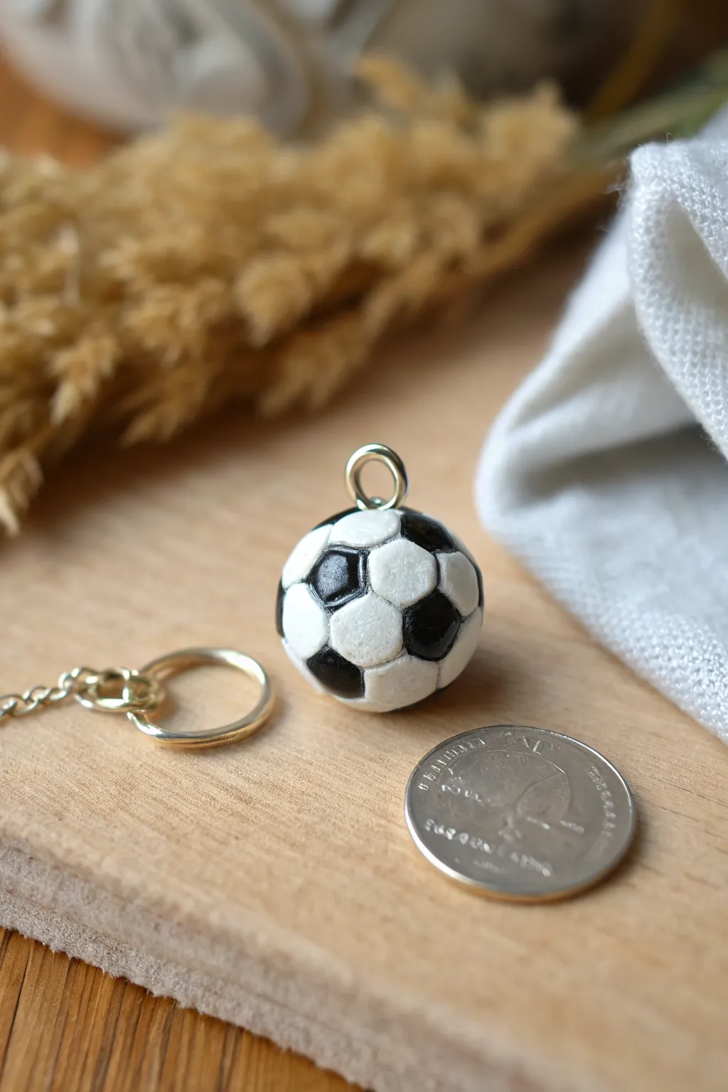 Tiny clay soccer ball charm, simple black-and-white details, styled minimally with a cozy studio vibe.