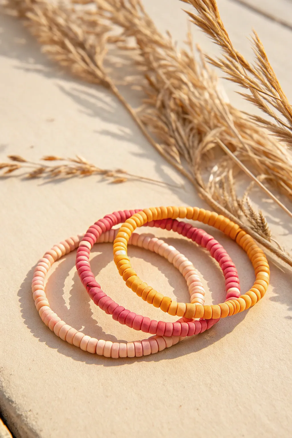 Sunset ombre heishi clay bead bracelet set in warm sand tones, minimalist summer style.