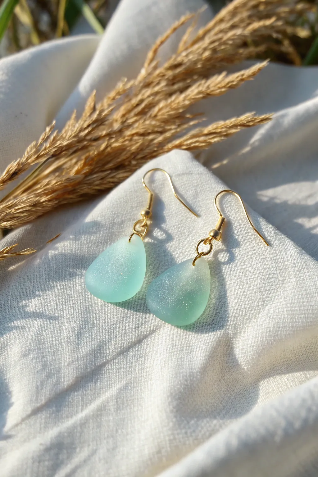 Frosted faux sea glass earrings in soft ocean tones, minimal linen styling and gentle glow.