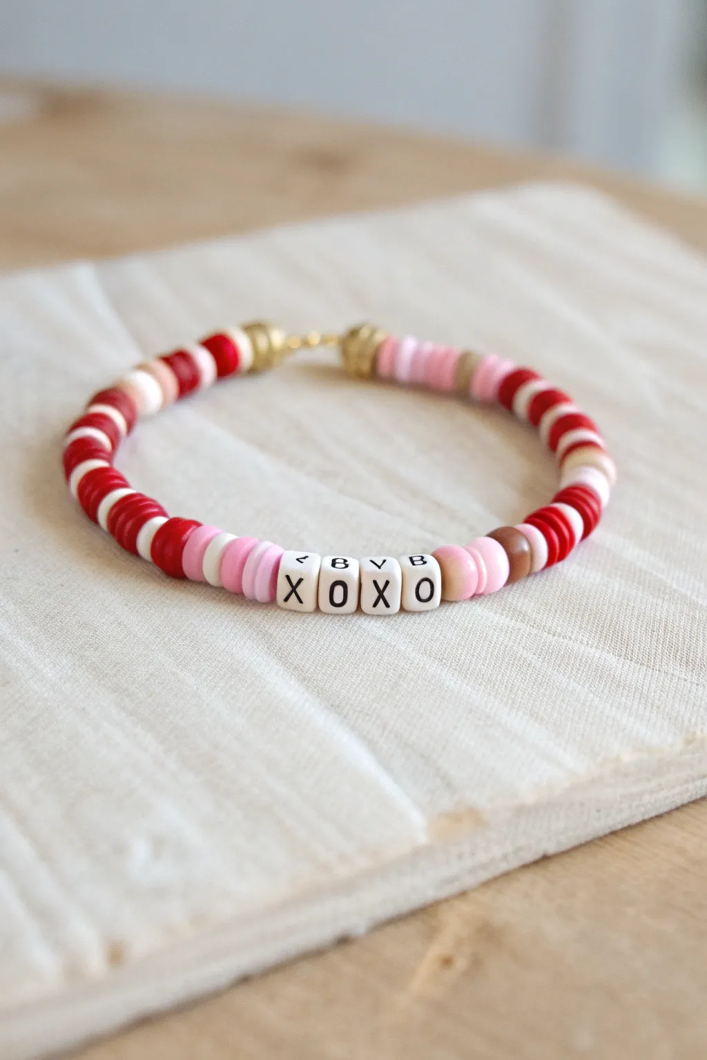 Romantic candy stripe clay heishi bracelet with XOXO center and subtle gold spacers.