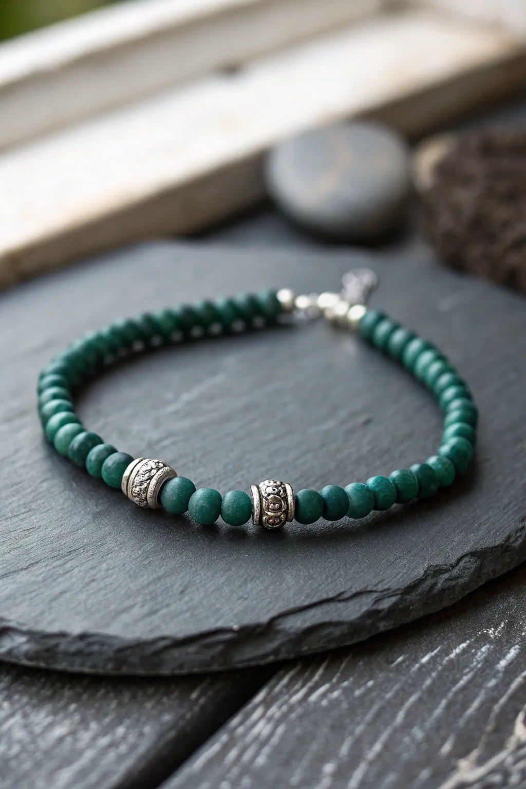 Emerald and silver clay bead bracelet on moody slate, minimalist magic with handcrafted charm