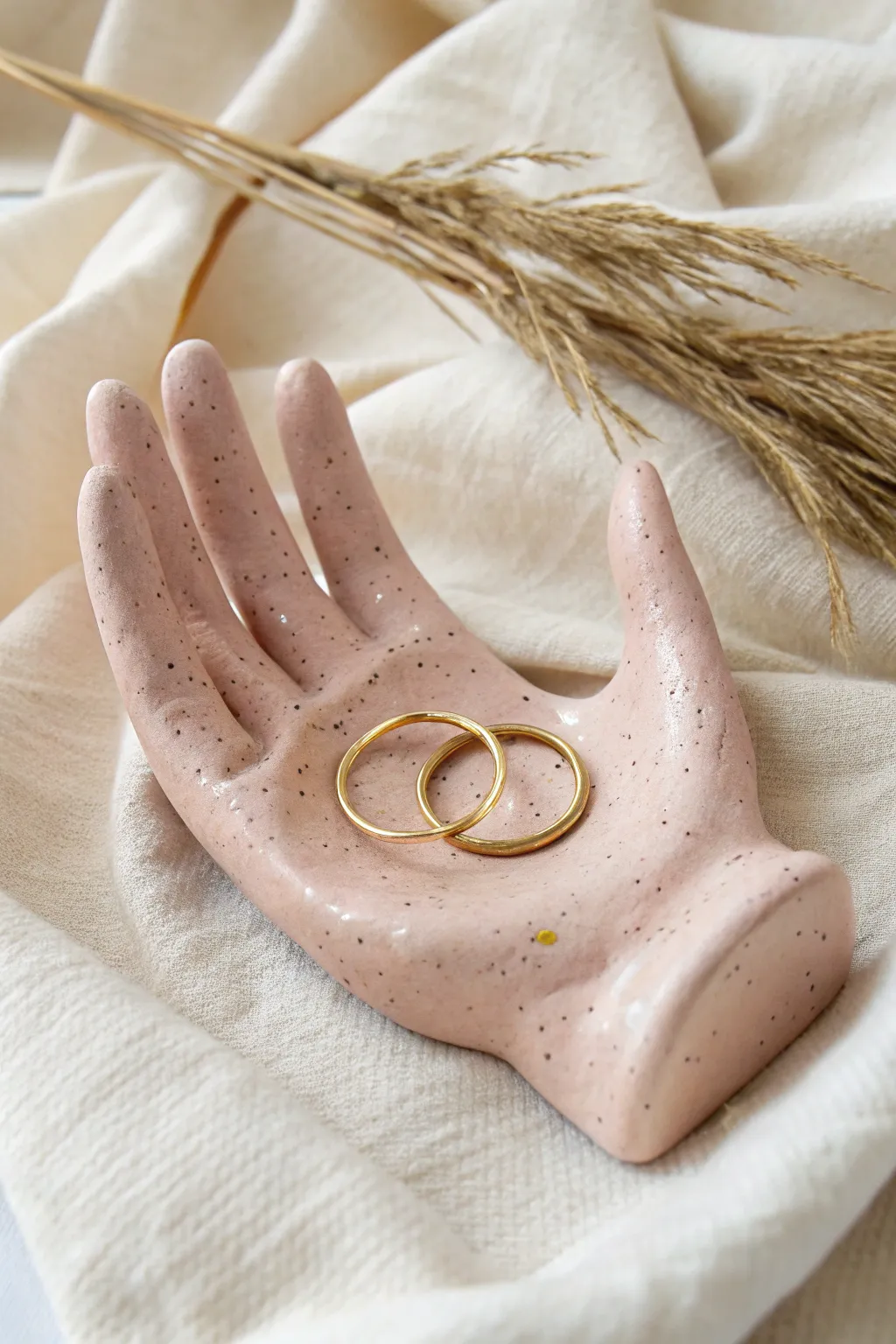 Palm-shaped air dry clay ring holder in soft blush, styled on linen for a calm minimalist look