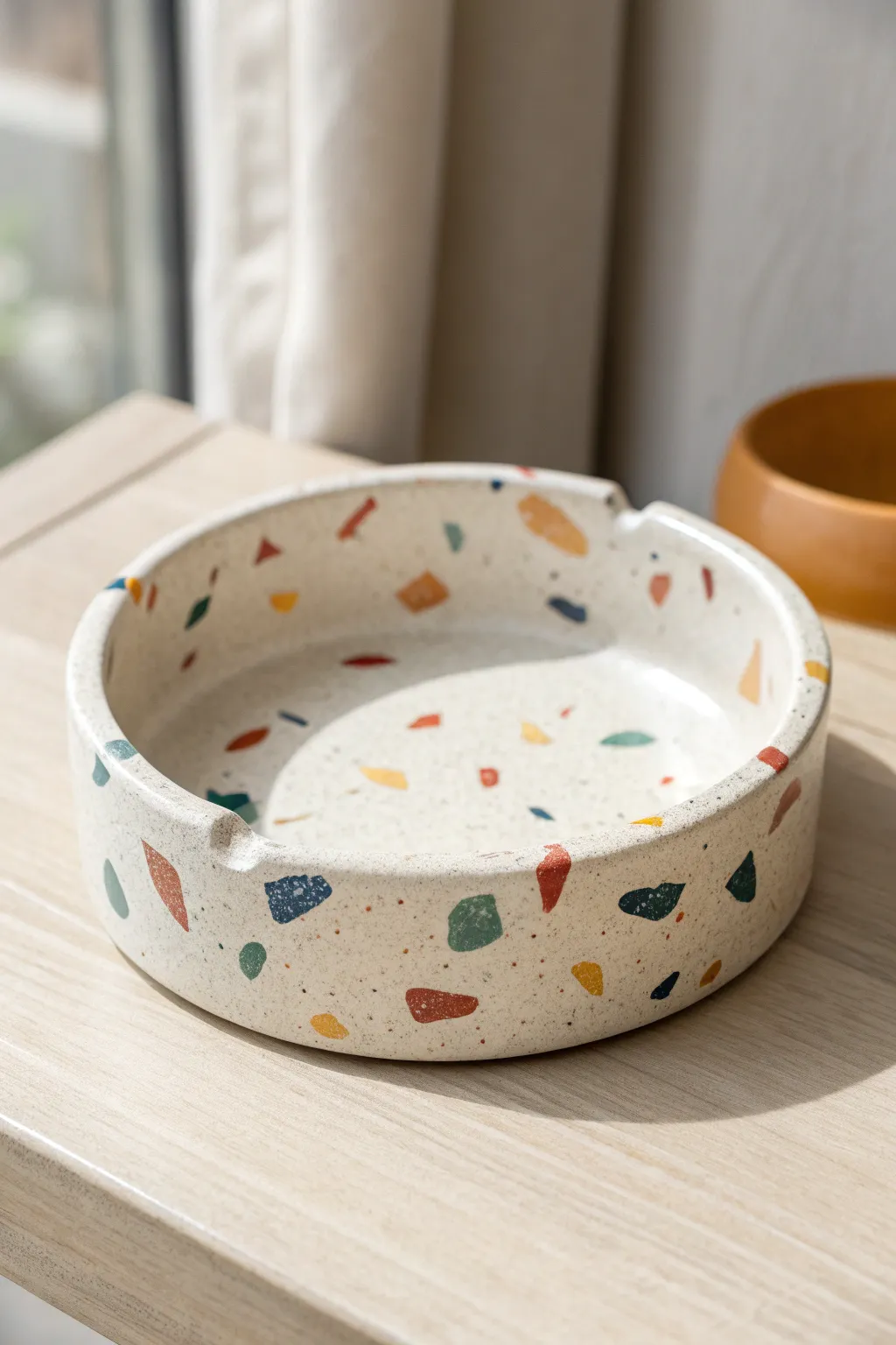 Terrazzo speckle air dry clay ashtray, glossy sealed and minimalist on a warm neutral backdrop