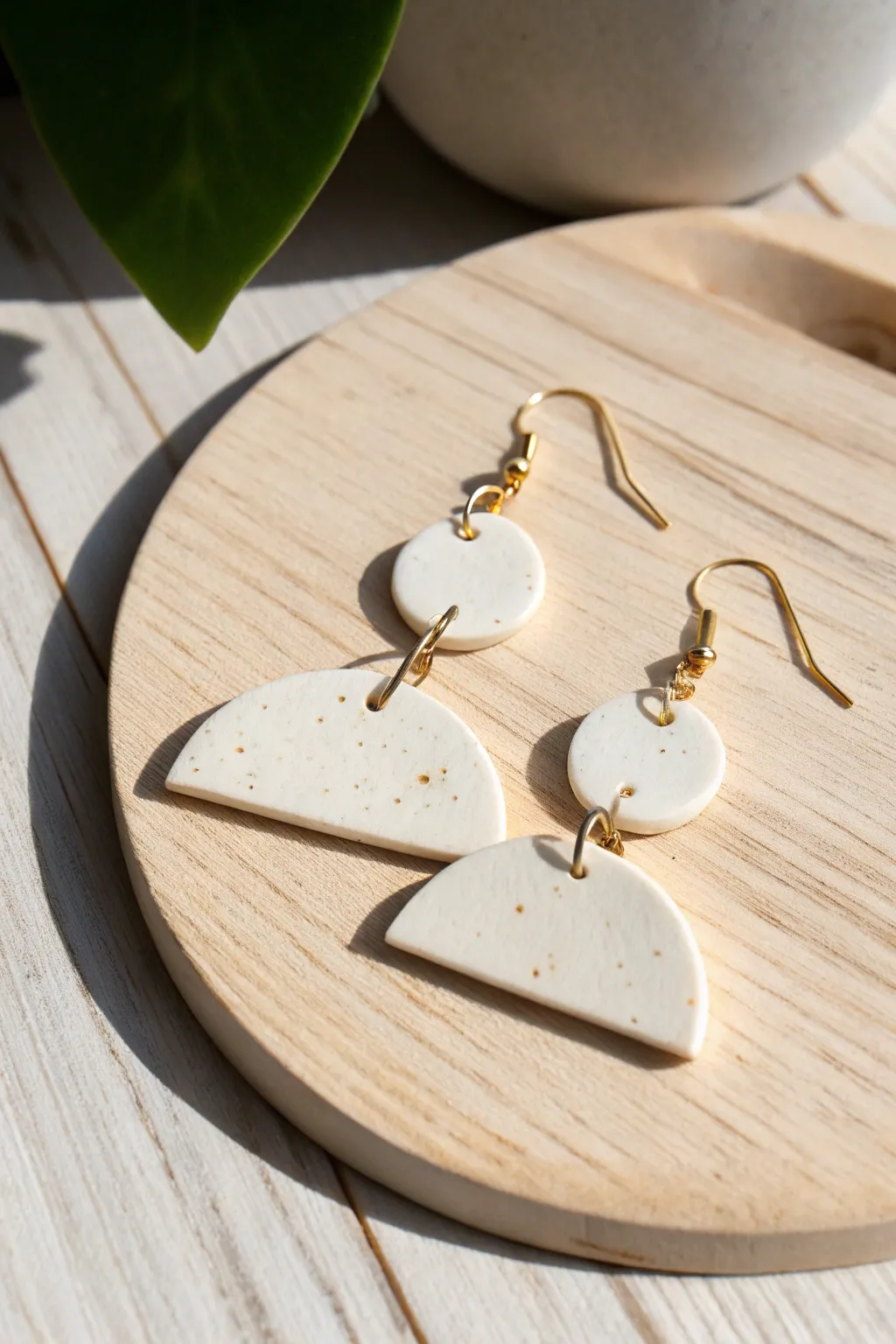 Minimalist half-moon air dry clay earrings with a satin finish, styled on pale wood.