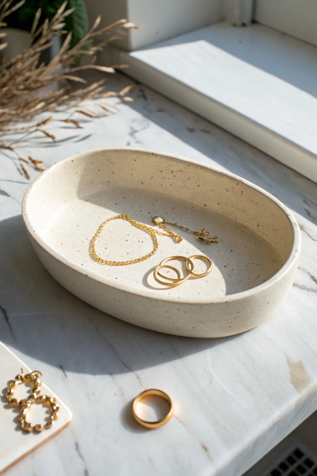 Raised-rim oval catchall dish keeps tiny studs and chains neatly in one calm spot