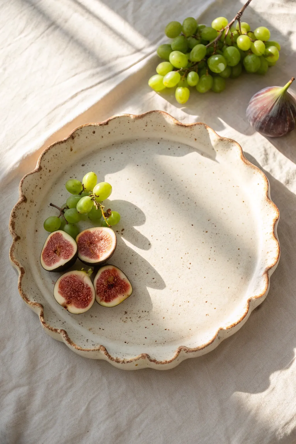 Organic wavy-edge ceramic platter with speckled glaze, styled simply with fresh fruit.
