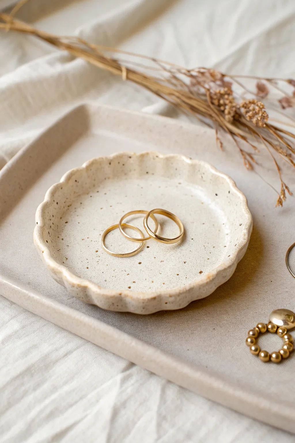 Round pinch-rim ring holder plate in soft clay tones, styled with rings for minimalist charm.
