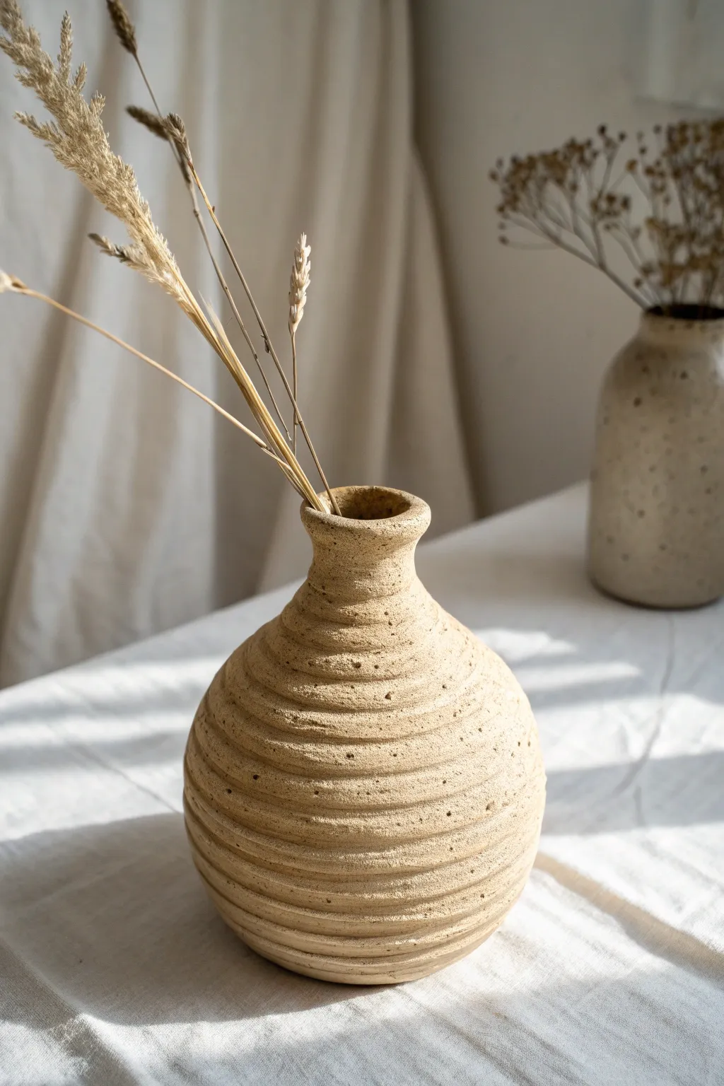 Coil-built mini vase with natural texture and a dried stem, perfect for simple clay projects.