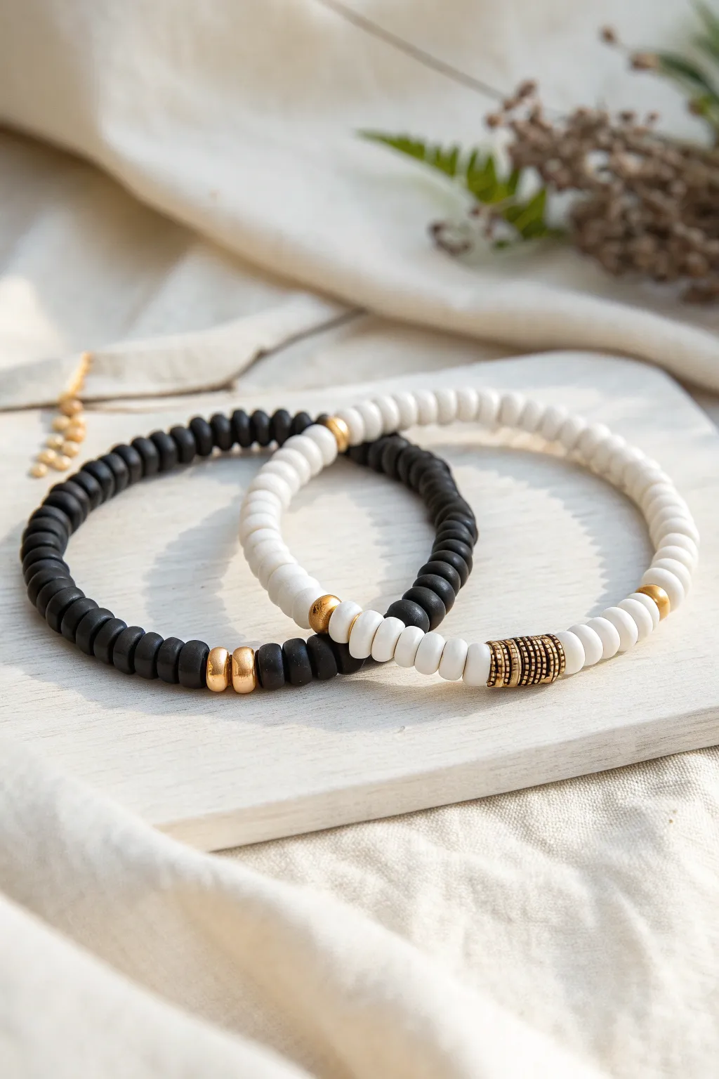 Monochrome heishi stack in black and white, finished with a tiny brushed gold accent bead.