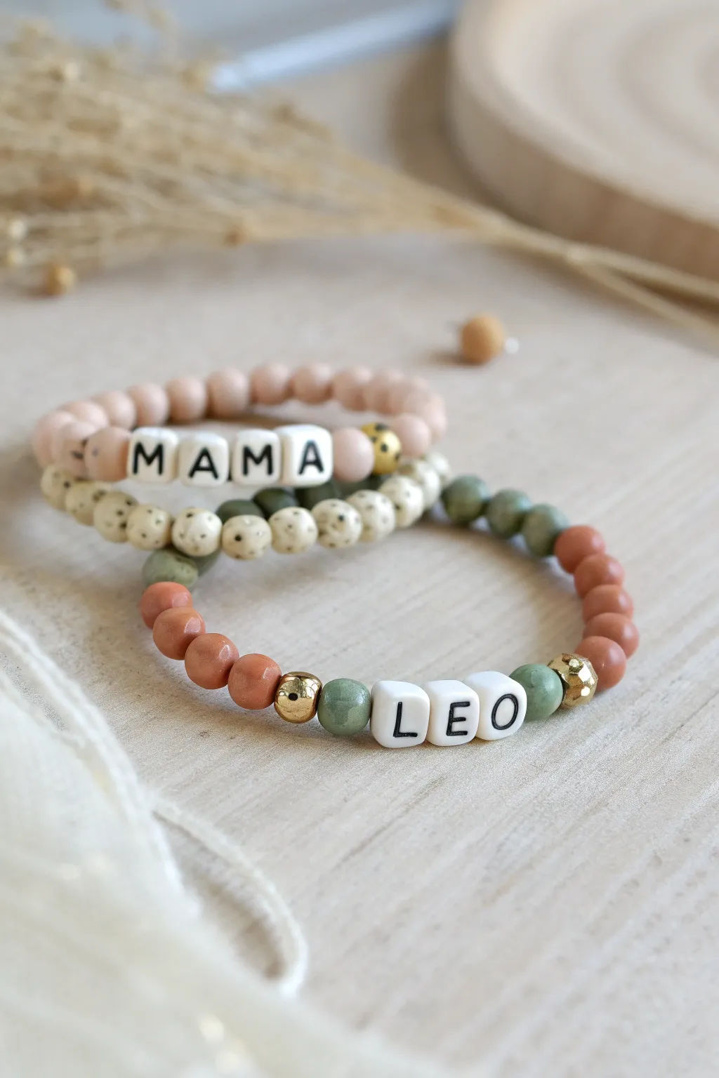 Matching Mama and mini clay bead word bracelets in soft neutrals with delicate spacers.