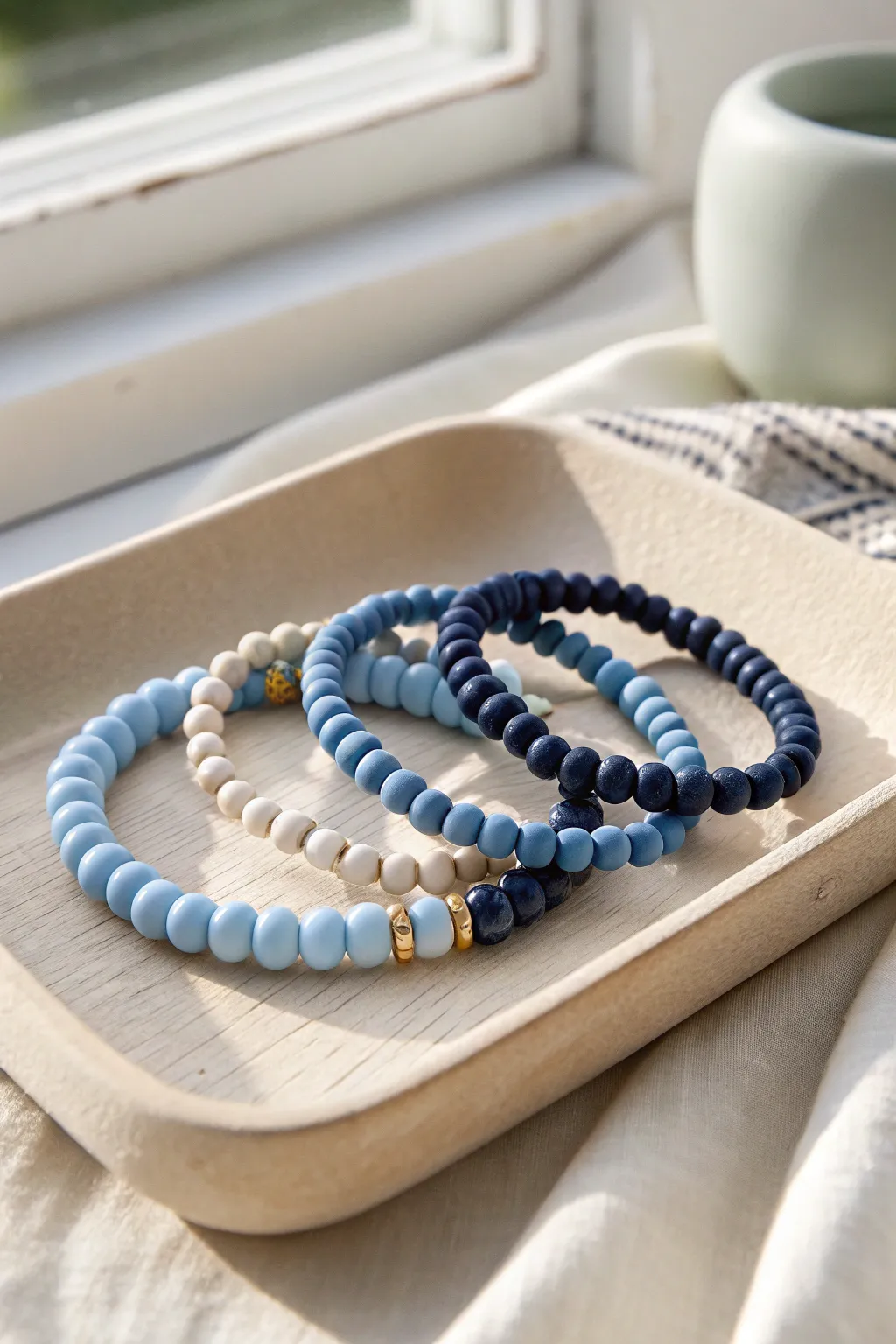 Monochrome clay bracelets in serene blues with a simple gold-bead accent, clean and minimal.