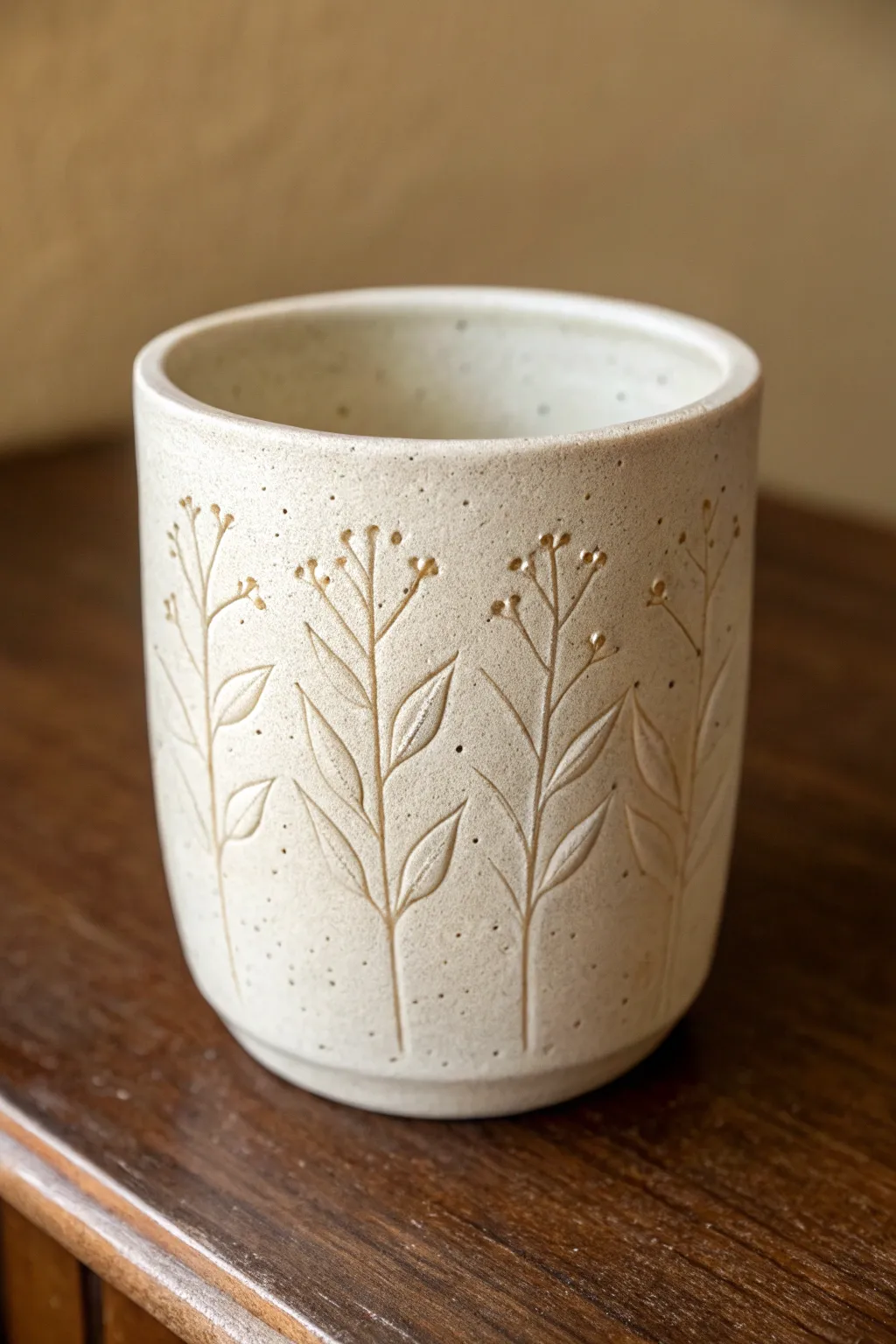 Minimal carved botanical panel on a matte clay cup, simple lines and Scandinavian calm.