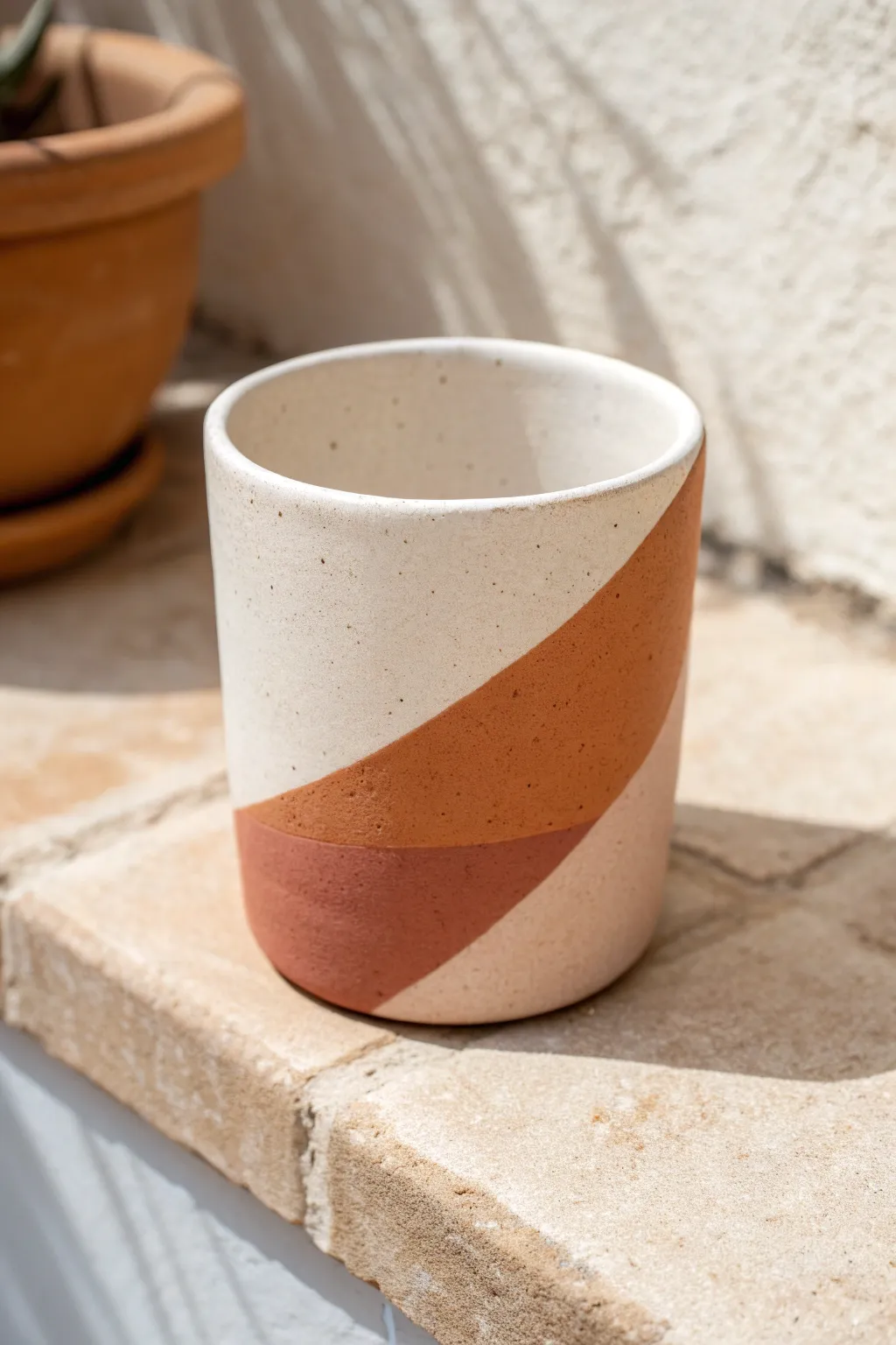 Modern color-block clay cup in terracotta and blush tones, minimalist and boho on a pale backdrop.
