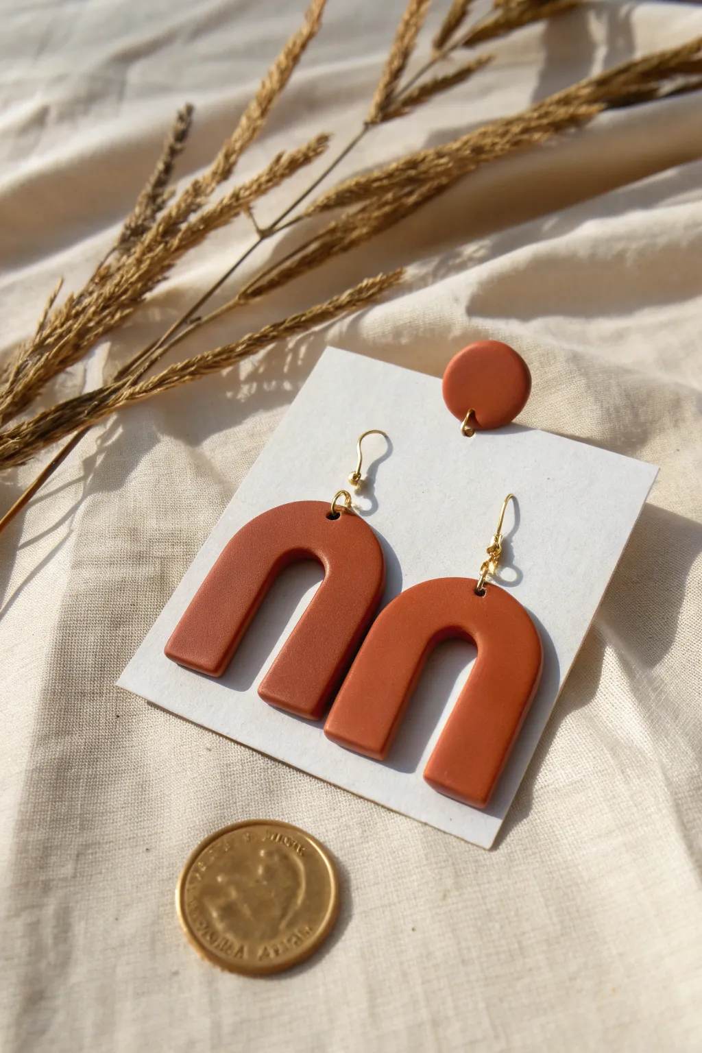 Modern arch polymer clay earrings in bold terracotta, styled simply with scale for impact.