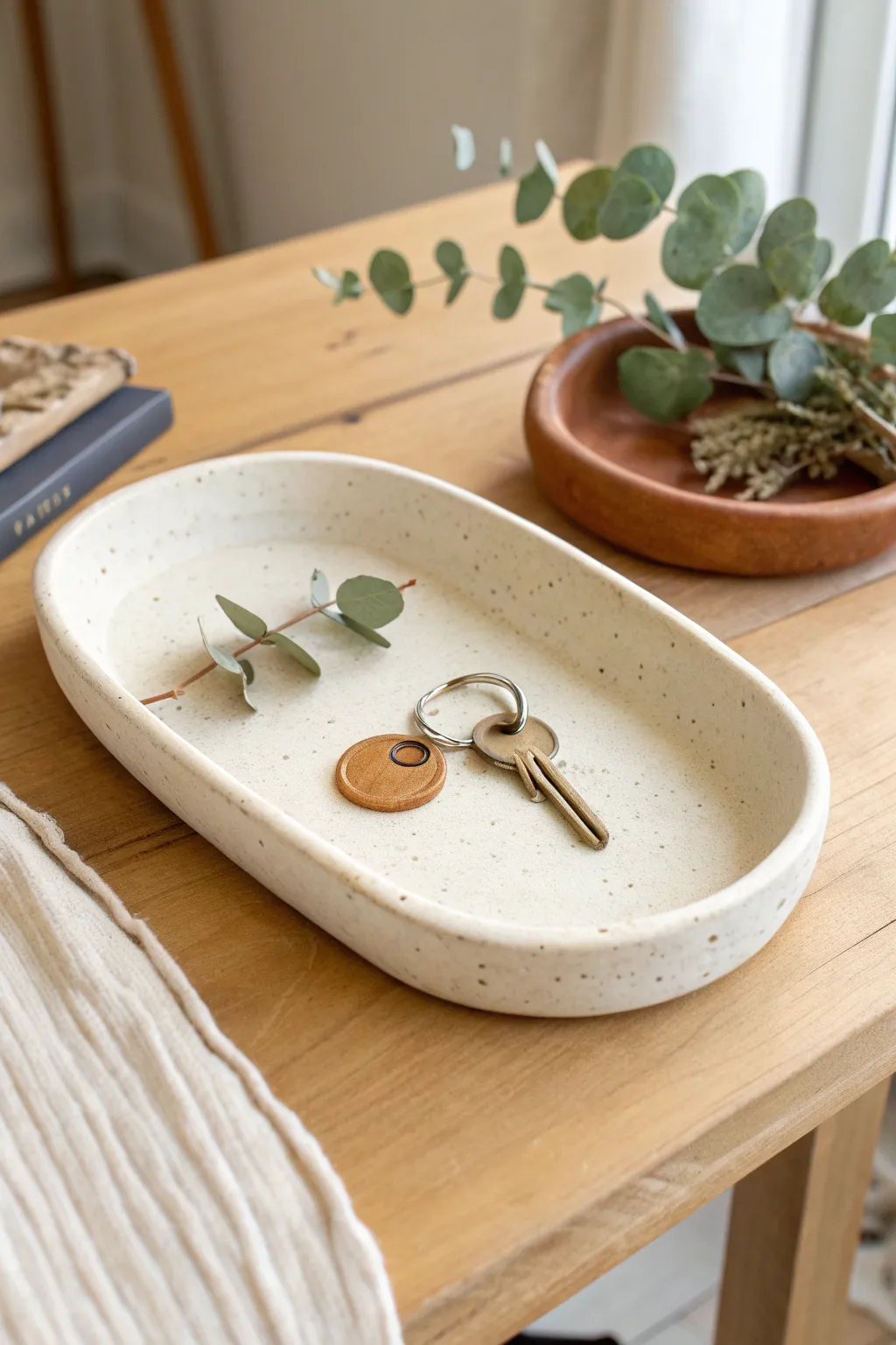 Simple oval clay key catchall tray in warm daylight, minimal styling, calm Scandinavian vibe