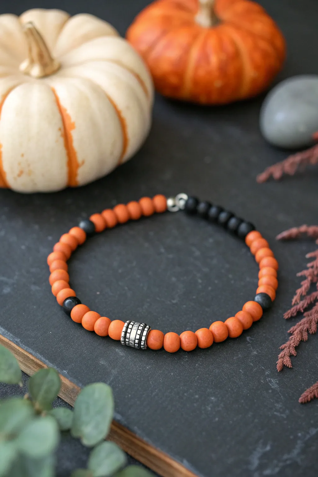 Orange and black heishi clay bead bracelet with subtle metallic spacers for a chic Halloween pop