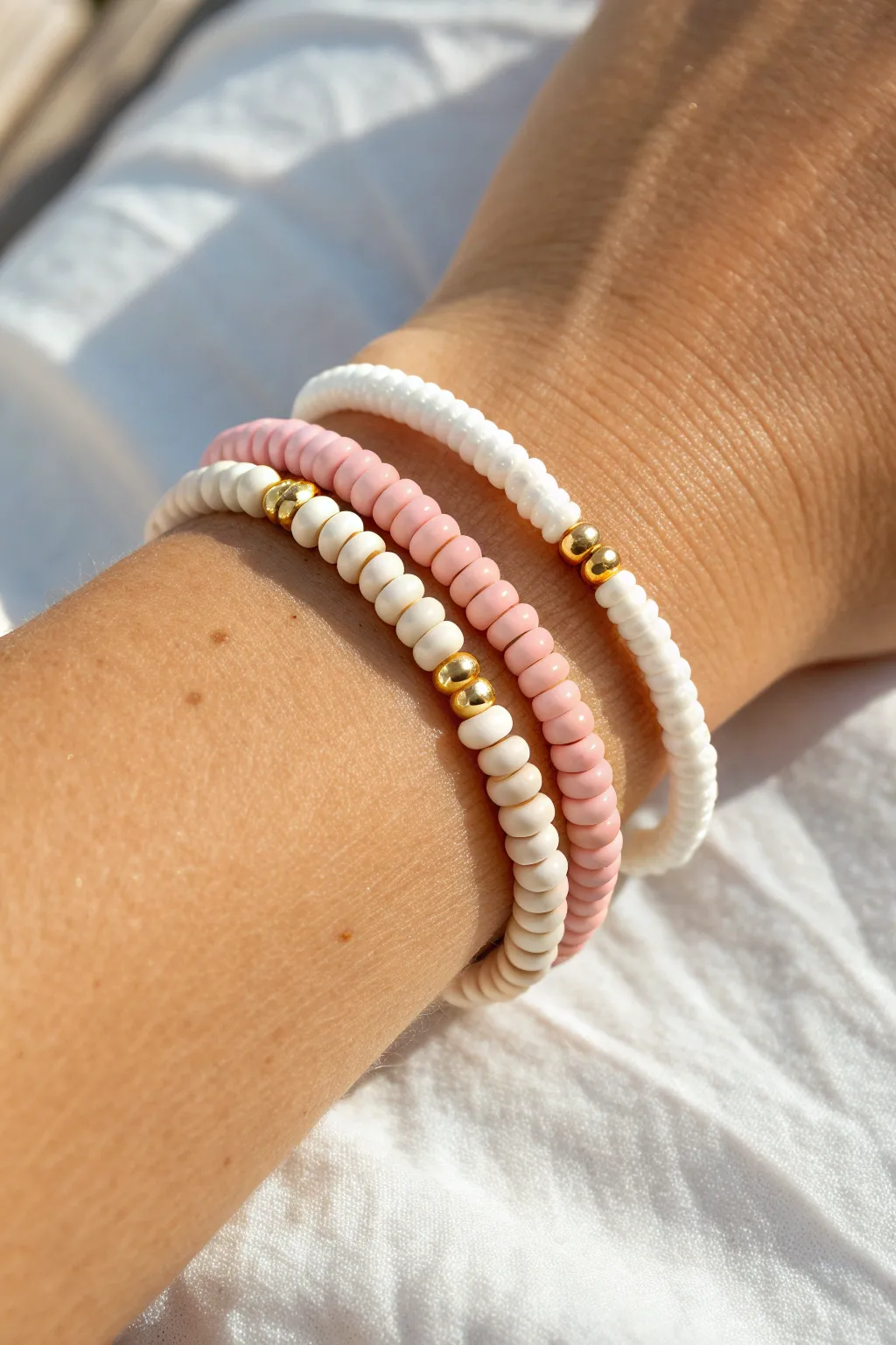 Pink and white candy stripe heishi bracelets stacked neatly for a sweet, minimalist look
