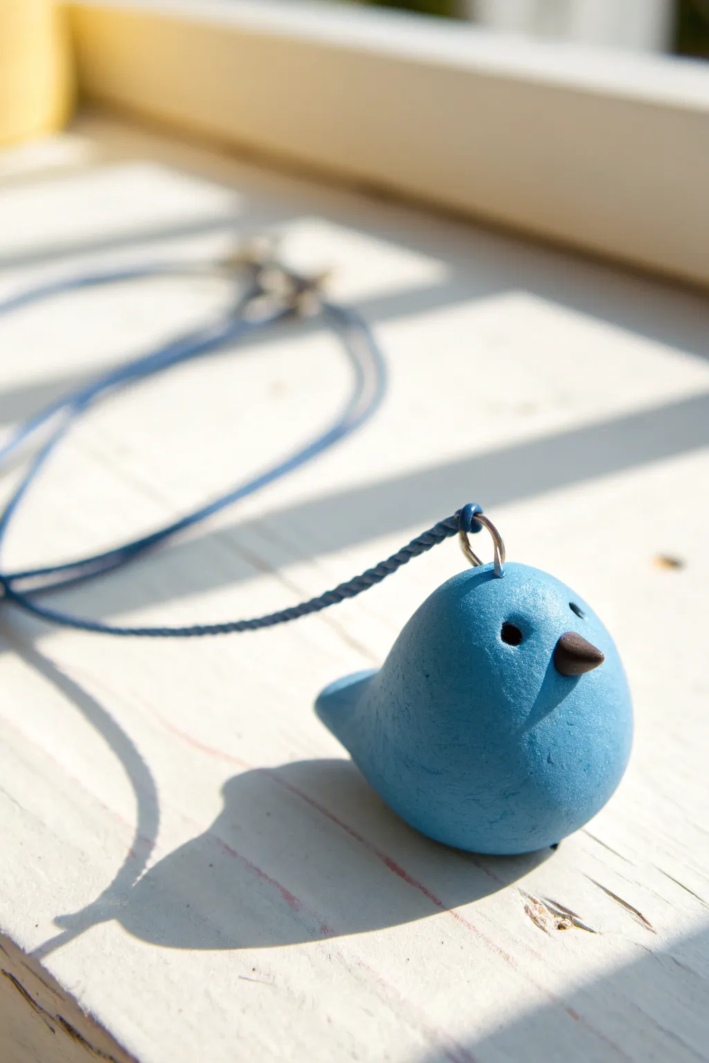 Round blue clay bluebird charm with a simple beak and wings, styled clean and bright.