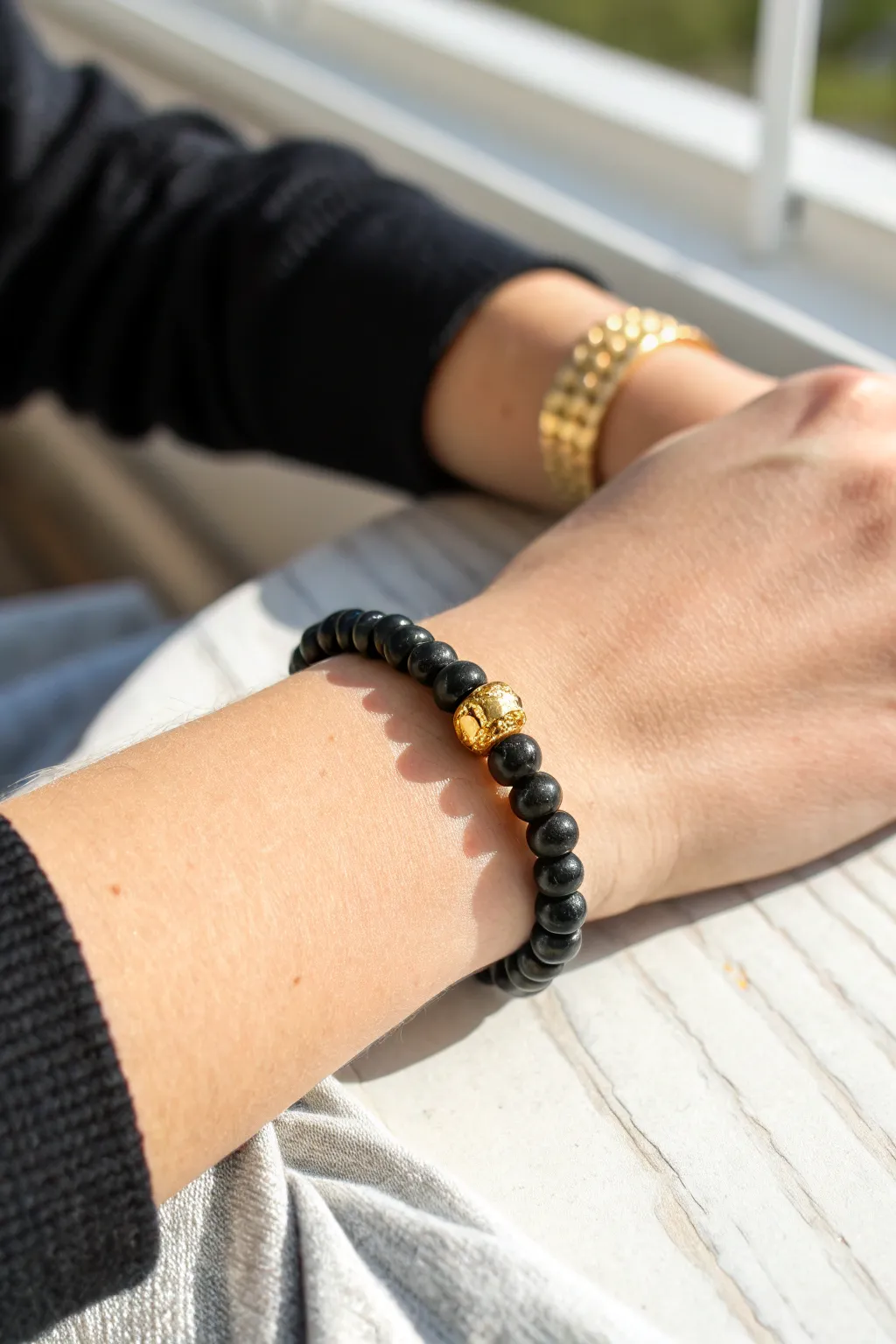 Sleek black clay heishi bracelet with a bold gold bead cluster for modern contrast